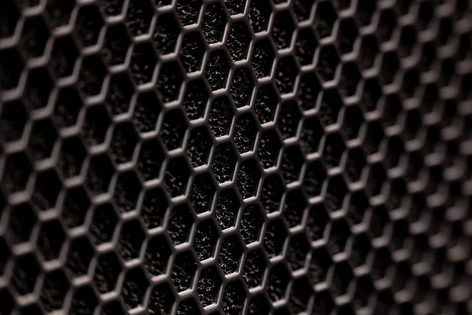Close-up of a metallic grille with a uniform hexagonal pattern — similar to baffle filter construction